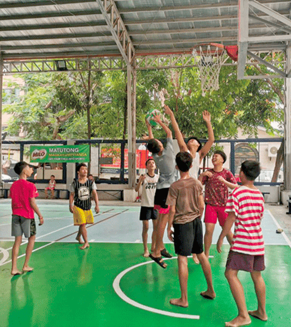 filipino kids playing basketball in barangay liga covered courts